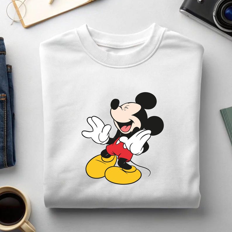 May include: White crew neck sweatshirt featuring a smiling Mickey Mouse graphic. The cartoon character is depicted with black ears, a red shirt, yellow shoes, and white gloves. The sweatshirt is made of a soft, comfortable material.