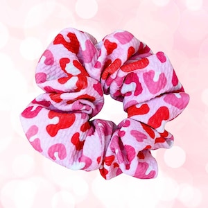 May include: Pink and red leopard print scrunchie for hair.