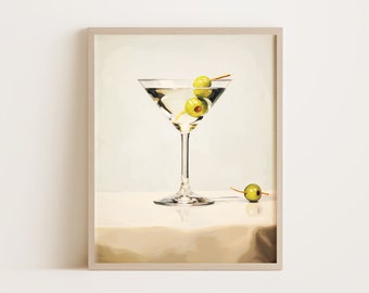 May include: A martini glass filled with a clear liquid and two green olives. The glass is sitting on a white surface with a single olive on the surface.