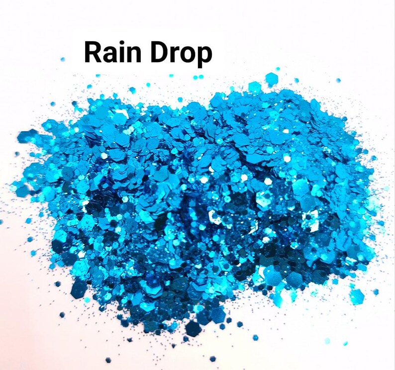 K&ouml;nnte beinhalten: Nahaufnahme eines Haufens t&uuml;rkisblauer Glitzer. Der Glitzer ist schillernd und hat verschiedene Gr&ouml;&szlig;en und Formen. Der Glitzer ist mit "Rain Drop" beschriftet.