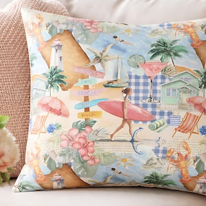May include: Square throw pillow with a beach-themed print. The design features a map, palm trees, a surfer, and beach huts in shades of blue, pink, and beige. The pillow is placed on a white sofa, suggesting a coastal or vacation theme.