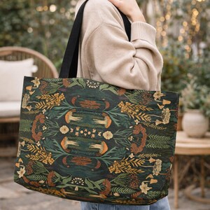 Woman wearing large dark green botanical tote bag, moody cottagecore style weekender bag with earthy nature print, everyday carryall purse