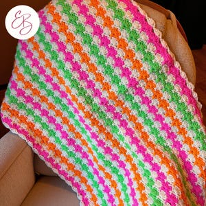 May include: A crocheted baby blanket with a scalloped edge in white, orange, pink, and green stripes.