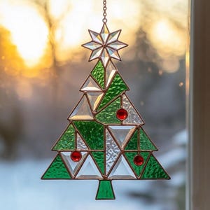 Könnte beinhalten: Glasfenster-Weihnachtsbaumschmuck mit Stern und roten Kugeln. Der Baum besteht aus grünen und klaren Glasteilen, die mit einem kupferfarbenen Metall umrahmt sind. Der Schmuck hängt an einer filigranen Kette, ideal für die Weihnachtsdekoration.