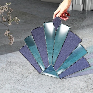 May include: A blue and teal stained glass sunburst design with a geometric pattern. The glass is textured and has a metallic finish.