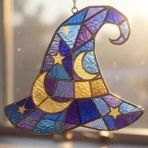 Könnte beinhalten: Bunter Hexenhut-Suncatcher aus Glas in Blau-, Lila- und Goldtönen. Der Hut zeigt einen Mond und Sterne, mit einer Kette zum Aufhängen. Das Design ist geometrisch, wobei jeder Glasabschnitt von einer dunklen Umrandung umgeben ist.