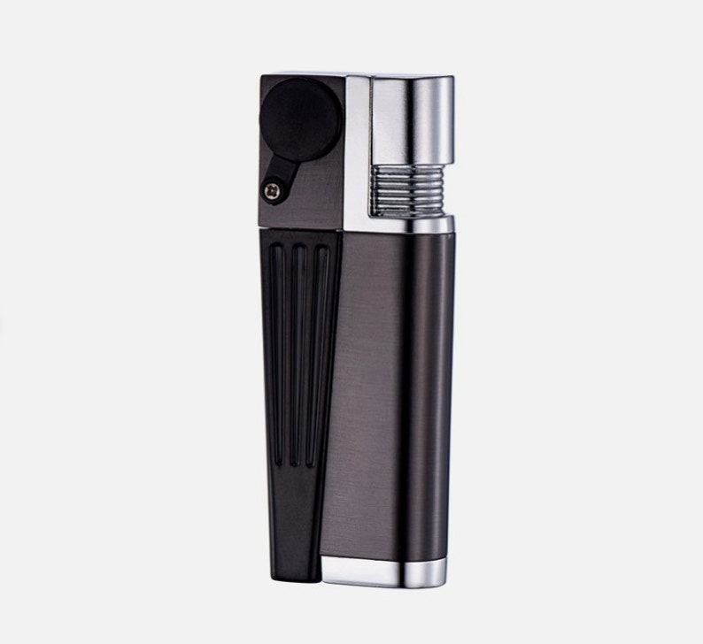 May include: A silver and black refillable butane lighter with a textured design. The lighter has a black plastic top and a silver metal body.