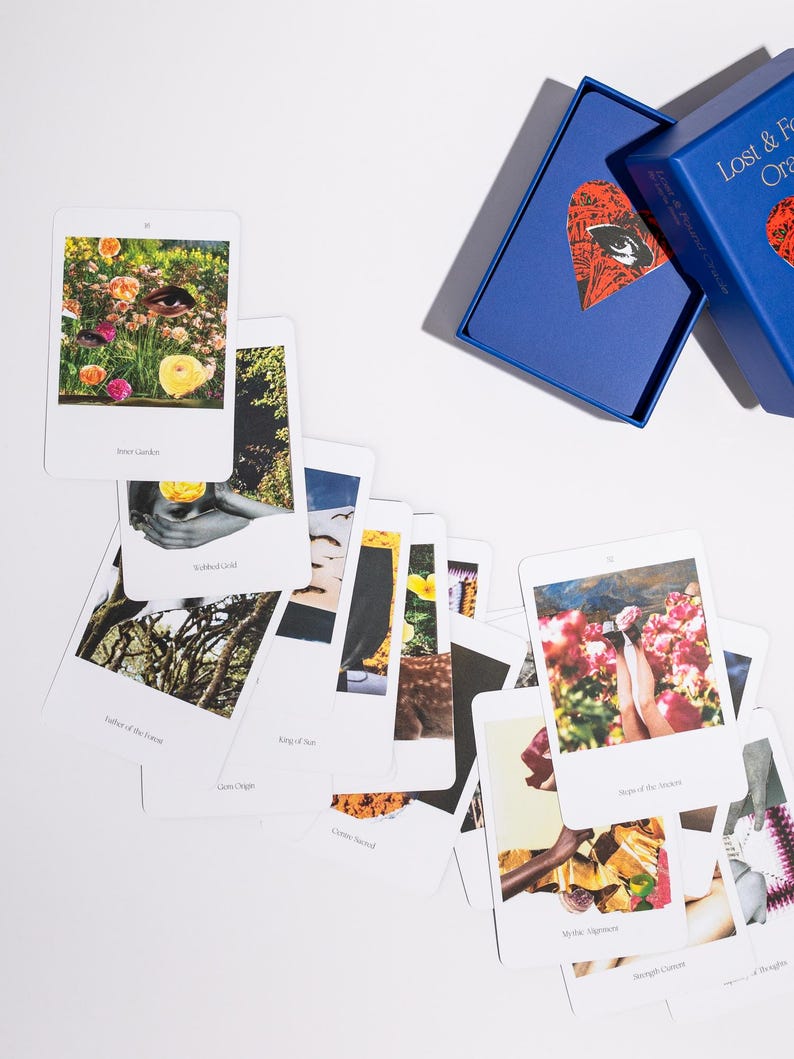 May include: A collection of oracle cards with various images and text, scattered on a white surface. The cards feature colorful illustrations and phrases. A blue box with the text "Lost & Found Oracle" is also present.