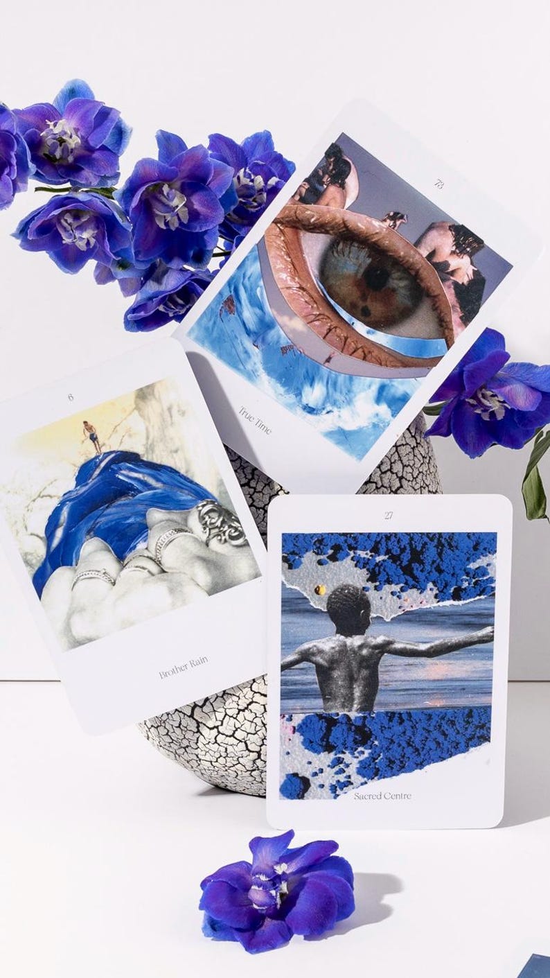 May include: Three tarot cards with surreal imagery, including an eye, a figure in water, and a person on a blue cloth. The cards are accompanied by vibrant purple flowers in a textured vase. The text on the cards reads "True Time", "Brother Rain", and "Sacred Centre".