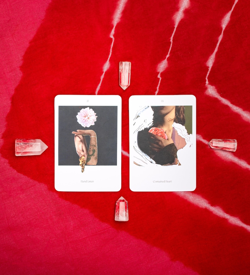 May include: Two tarot cards with illustrations and text, surrounded by clear quartz crystals, are displayed on a red fabric with white streaks. One card shows a hand holding a flower, the other a person holding a heart.