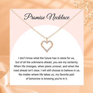 May include: A rose gold-toned necklace featuring a heart-shaped pendant encrusted with small clear stones. The display card includes the text Promise Necklace and a long message about the future, certainty, and choosing to believe in us.