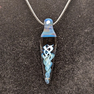 May include: A glass pendant necklace with a silver chain. The pendant is a clear, teardrop shape with blue and white swirling designs inside. The top of the pendant has a blue and white color gradient.