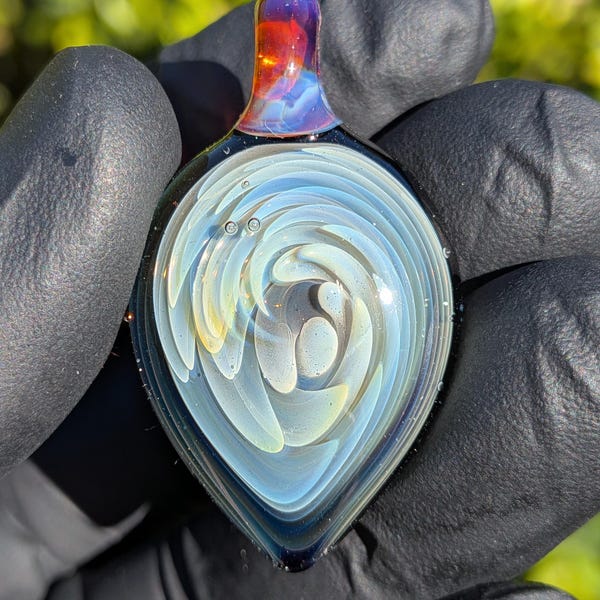 Handblåst silverhänge i implosionsglas tillverkat av pyrexborosilikat. Levereras med halsband och ask.
