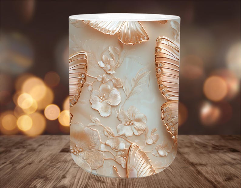 May include: A cylindrical decorative lamp with a cream-colored background. The lamp features a relief design of butterflies and flowers in shades of gold and cream. The lamp is placed on a wooden surface.