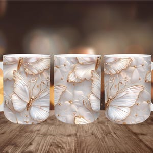May include: White ceramic mug featuring a 3D butterfly design with gold accents. The butterflies are set against a background of white flowers and gold embellishments. The mug has a white handle.