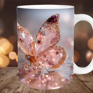 May include: White ceramic mug featuring a detailed illustration of a pink butterfly with sparkling embellishments. The butterfly has intricate wing patterns and is adorned with gems. The mug has a white handle and a blurred background with bokeh lights.