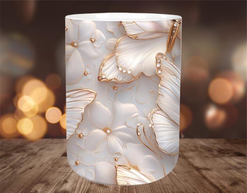 May include: A white ceramic mug featuring a repeating pattern of white flowers and butterflies with gold accents and embedded crystals. The design is embossed, creating a 3D effect. The mug has a smooth, glossy finish.