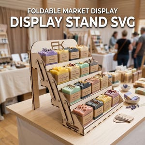 Könnte beinhalten: Ein faltbarer Markt-Präsentationsständer aus Holz mit mehreren Ebenen, der verschiedene farbige Seifen enthält. Der Ständer trägt den Text "FOLDABLE MARKET DISPLAY DISPLAY STAND SVG". Jede Seife ist mit ihrem Duft gekennzeichnet, wie z. B. "Lavendel".