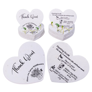 May include: Heart-shaped seed paper with the text "Thank You!" and "Plant me, I grow Wildflowers." The paper includes a planting guide with instructions. The image shows several stacks of the heart-shaped paper with small sprouts.