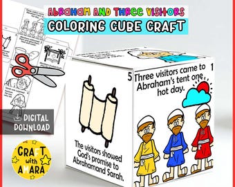 May include: A paper craft cube featuring the Abraham and Three Visitors story with black and white line art illustrations, colored figures, and text. The cube displays a scroll, three figures, and narrative text. A flat template and scissors are visible.