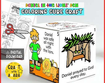 May include: A white cube craft with illustrations and text from the story of Daniel in the Lion's Den. The cube features images of Daniel, lions, and the text "Daniel was safe all night with the lions." and "Daniel prayed to God every day."