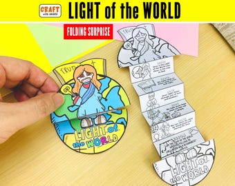May include: A paper craft titled Light of the World featuring a circular design with a colorful illustration of a figure holding a lightbulb over a globe. An accordion-folded strip of black and white paper with text and illustrations extends from the center.