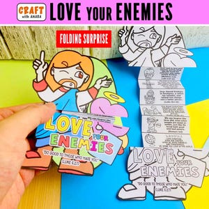 May include: A paper craft activity titled Love Your Enemies featuring a colorful illustration of a figure with orange hair and a blue tunic, alongside a black and white accordion-folded strip with text and line drawings for coloring.