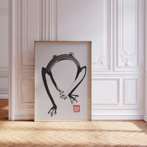 May include: A black and white ink painting of a frog in a minimalist style, framed in a gold frame. The painting is on a white background and has a red seal in the bottom right corner.