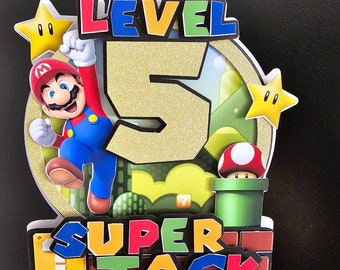 Könnte beinhalten: Ein Kuchentopper mit einer Comicfigur, der Zahl 5 und den Worten "Level" und "Super Jack". Die Figur trägt einen roten Hut, eine blaue Latzhose und weiße Handschuhe. Die Zahl 5 ist golden mit Glitzer. Die Wörter sind in einer bunten, blockartigen Schrift.