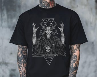 Könnte beinhalten: Schwarzes T-Shirt mit einem detaillierten schwarz-weißen Grafikdesign einer Kapuzenfigur mit gehörntem Schädel, erhobenen Händen und geometrischen Formen. Das Design ist in Grautönen gehalten. Das T-Shirt hat einen klassischen Rundhalsausschnitt.