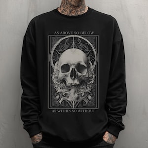 May include: Black sweatshirt featuring a detailed skull graphic with the text "AS ABOVE SO BELOW" above and "AS WITHIN SO WITHOUT" below. The skull is centered within a geometric design, creating a gothic aesthetic.
