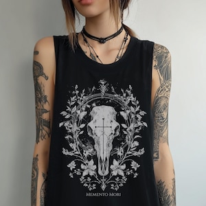 Könnte beinhalten: Schwarzes Tanktop mit einem weißen Schädel-Design, einem Kreuz und floralen Elementen. Der Text "Memento Mori" ist darunter gedruckt. Das ärmellose Top hat einen runden Ausschnitt.
