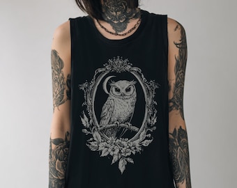 May include: Black vest top with a detailed owl illustration in a decorative frame. The design is in grey and white, with floral and crescent moon accents. The sleeveless top has a classic, casual style.