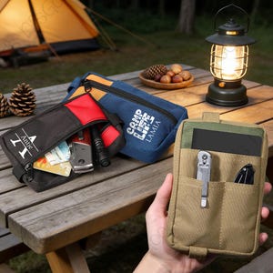 May include: Several zipped pouches in black, red, blue, and tan. Some are open, displaying contents such as knives, cards, and a torch. The pouches are on a wooden table, with a lantern and camping tent in the background, suggesting outdoor use.