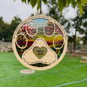 May include: A wooden paw print ornament with a stained glass design and a heart-shaped photo cutout. The ornament has the text "Molly, 2023 A special place in our hearts for our departed fur baby" and "PHOTO HERE" on it.