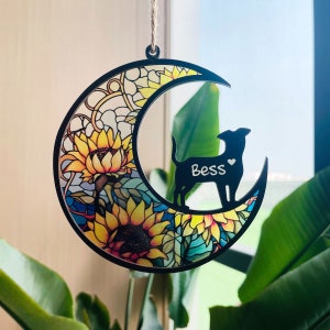 May include: Black wooden crescent moon ornament with a sunflower and stained glass design. A black silhouette of a dog is in the center with the name "Bess" written on it.