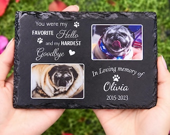 May include: A rectangular black slate memorial plaque featuring two color photographs of a pug. The text reads: You were my FAVORITE Hello and my HARDEST Goodbye, In Loving memory of Olivia, 2015-2023, accompanied by paw print and heart icons.