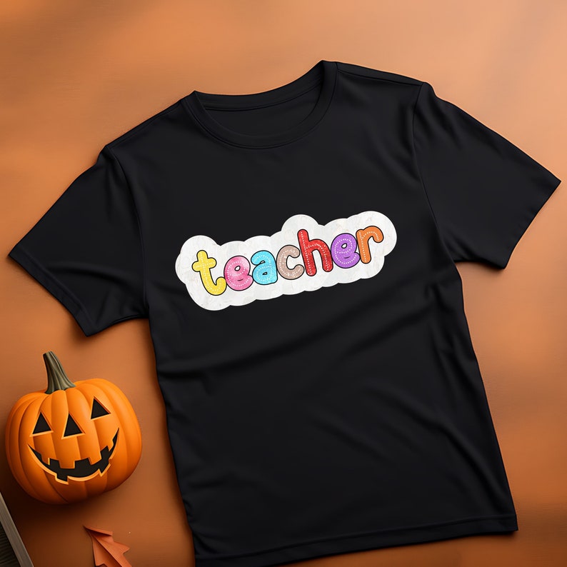 May include: Black t-shirt with a white cloud graphic that says "teacher" in colourful letters.
