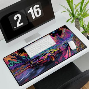 May include: A large, rectangular mouse pad featuring a vibrant, colorful illustration of a sports car racing on a road. The design incorporates neon colors and a psychedelic landscape. A white keyboard and mouse are on the pad.