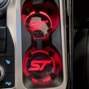 May include: Two red illuminated cup holders with the letters "ST" in white inside each holder.