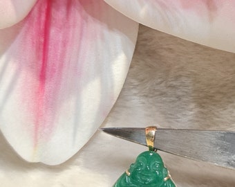 May include: A green jade pendant of a smiling Buddha, carved in detail, with a gold bail.