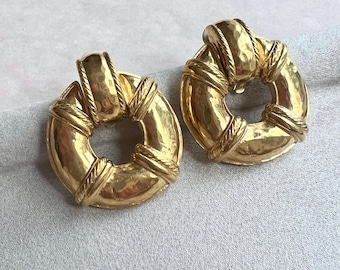 May include: A pair of gold-toned hoop earrings with a textured finish and a rope-like design around the edges.
