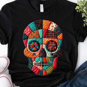 Könnte beinhalten: Schwarzes T-Shirt mit einem farbenfrohen Patchwork-Schädel-Design. Der Schädel besteht aus verschiedenen Stoffmustern in Rot-, Orange-, Blau- und Grüntönen. Das Design hat ein genähtes Aussehen und wirkt dadurch gesteppt. Ein lässiges Kleidungsstück.