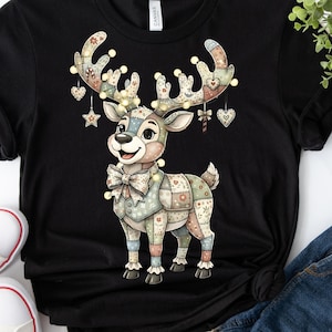Könnte beinhalten: Schwarzes T-Shirt mit einem Patchwork-Rentier-Design. Das Rentier hat große Geweihe, die mit Lichtern und hängenden Ornamenten verziert sind. Das Design verwendet Pastellfarben und Muster und schafft eine festliche und charmante Ästhetik.