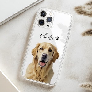 Pode incluir: Capa de telemóvel transparente com um retrato de golden retriever. A capa tem o nome "Charlie" em escrita cursiva e uma pegada. A pelagem do cão é castanho claro e a capa tem um acabamento brilhante.