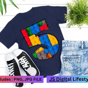 May include: A navy blue t-shirt featuring a graphic of the number 5 made from colourful Lego blocks. The text "includes: PNG, JPG FILE" is at the bottom of the image. The text "JS Digital Lifestyle" is at the bottom of the image.