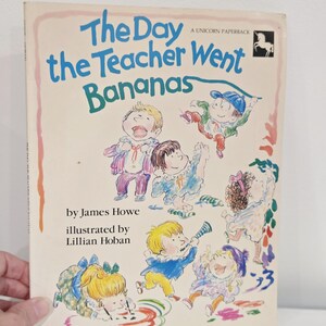 May include: A white ceramic mug with a black handle and the text "But First, Coffee" in a black, handwritten-style font. The mug is on a white surface.