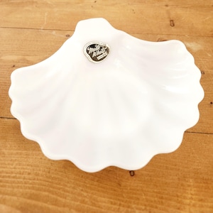May include: A white milk glass shell-shaped dish with a gold sticker that reads "Milk White" in a cursive font.
