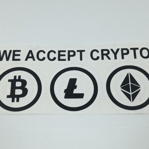 May include: A white sign with black text that reads "WE ACCEPT CRYPTO".  Three black and white circles with cryptocurrency symbols are below the text. The symbols are Bitcoin, Litecoin, and Ethereum.