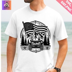 K&ouml;nnte beinhalten: Wei&szlig;es T-Shirt mit schwarzem Grafikdesign. Das Design zeigt eine amerikanische Flagge, Berge, Kiefern, einen Kompass und einen Jeep. Die Worte "SVG, DXF, PNG" stehen oben rechts. Das Parin Boutique-Logo befindet sich oben links.
